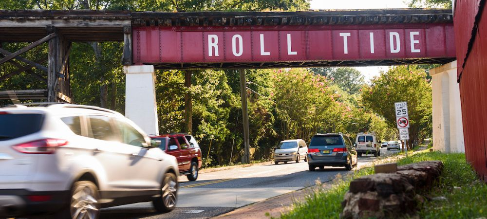 cars pass under a bridge with the words roll tide spray painted on the side 