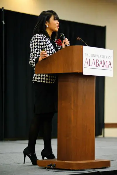 sheena standing at a podium and talking into a mic 