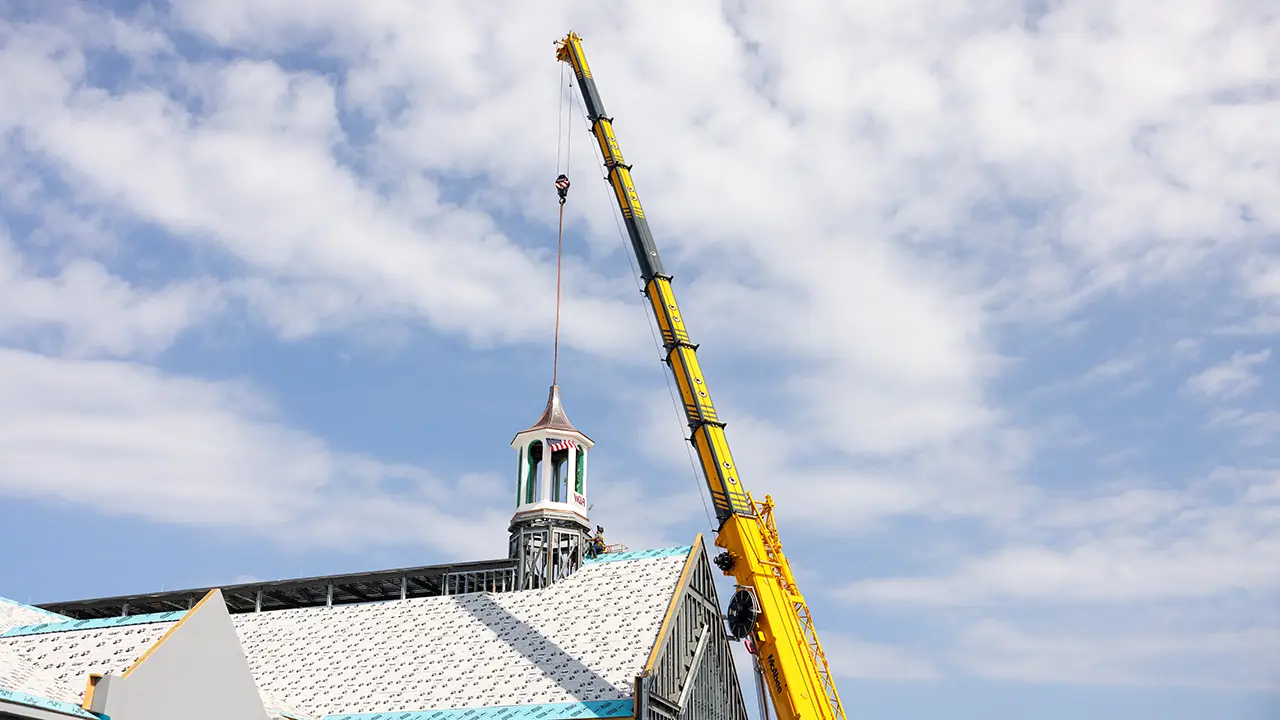 A crane lifts a cupola into place on the roof of the University of Alabama’s new Student Well-Being Hub.