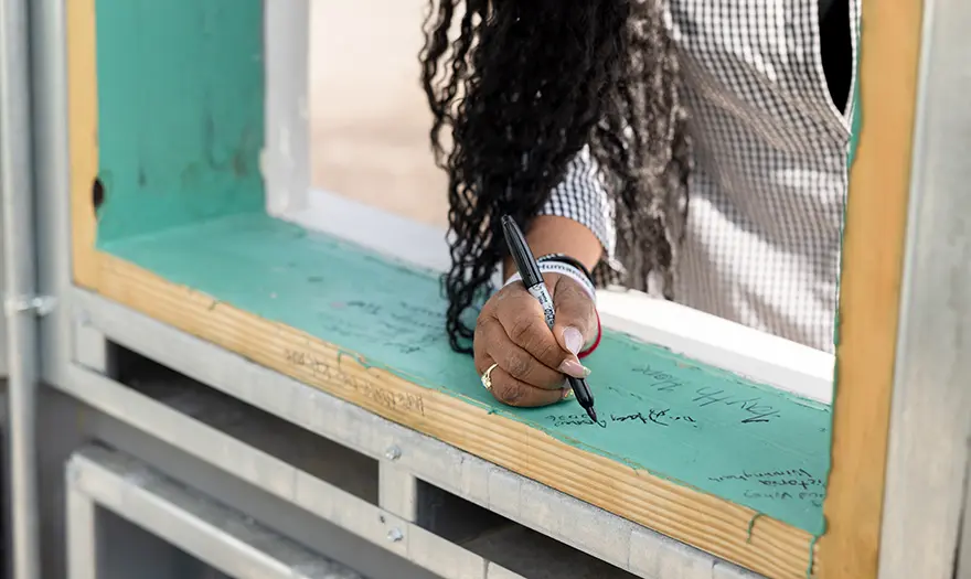 A person signing the cupola with a sharpie.