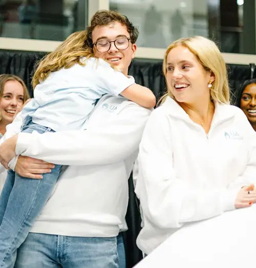 UA Miracle president Myles Hudson hugs a Miracle kid during an event.