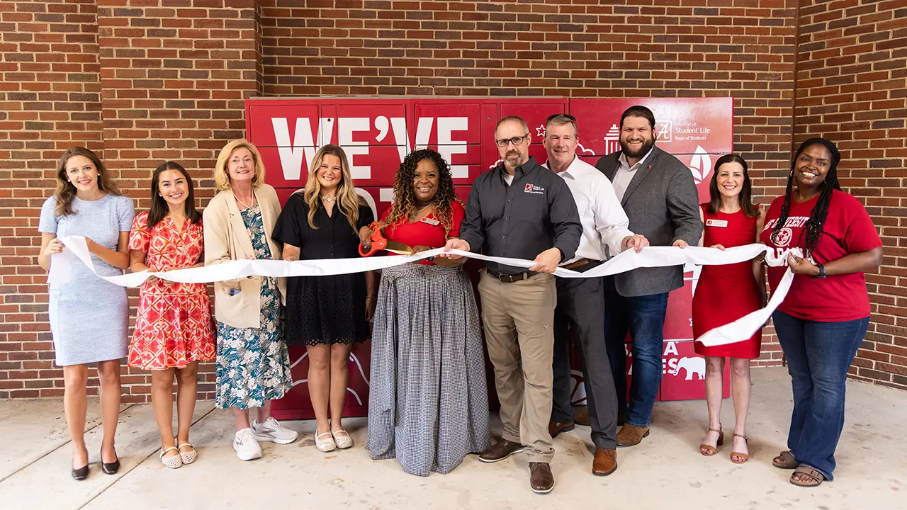 Members of Student life and Alpha Gamma Delta pose for a ribbon-cutting photo in front of the new BamaCares food lockers.